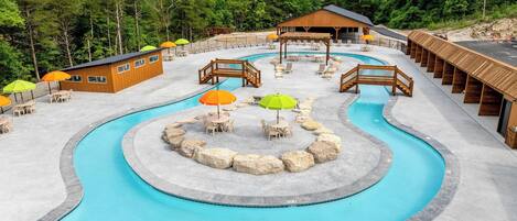 A resort with a large pool, wooden deck areas, and a mountain backdrop.