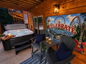 A hot tub with a wooden deck, a table with chairs, and a mural with a Ferris wheel.