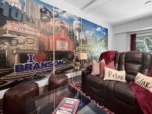 A living room with a large wall mural, a leather sofa, and a glass coffee table.