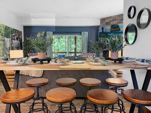 A modern kitchen with a central island, bar stools, and a large window with curtains.