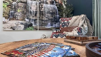 Une pièce décorée d’une grande fresque représentant une cascade, d’un canapé à motifs et d’une table en bois agrémentée d’un objet décoratif.