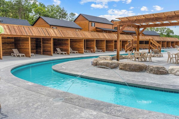A pool area with lounge chairs, wooden deck, and a wooden pergola.