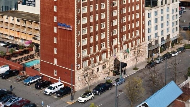 A high-rise hotel with a prominent red and beige facade, multiple floors, and a large sign at the top. - Seattle | Courtyard Calm Stay | Gym + Walkable (Seattle)