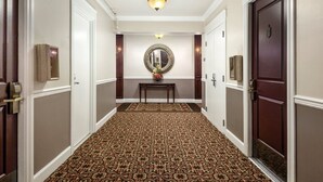 A hallway with patterned carpet, a mirror, and a table with flowers. - Seattle | Courtyard Calm Stay | Gym + Walkable (Seattle)
