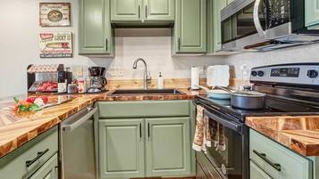 A kitchen with green cabinets, a microwave, a stove, and a coffee maker.