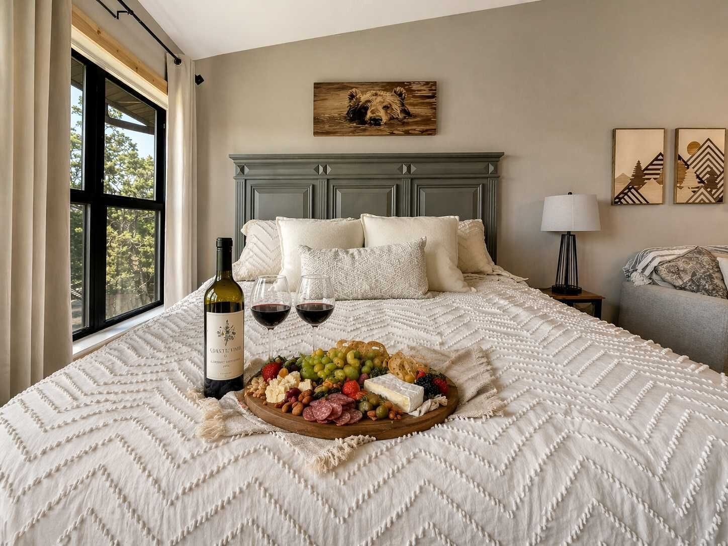 Habitación de hotel con cama, una botella de vino, copas y una bandeja de frutas.
