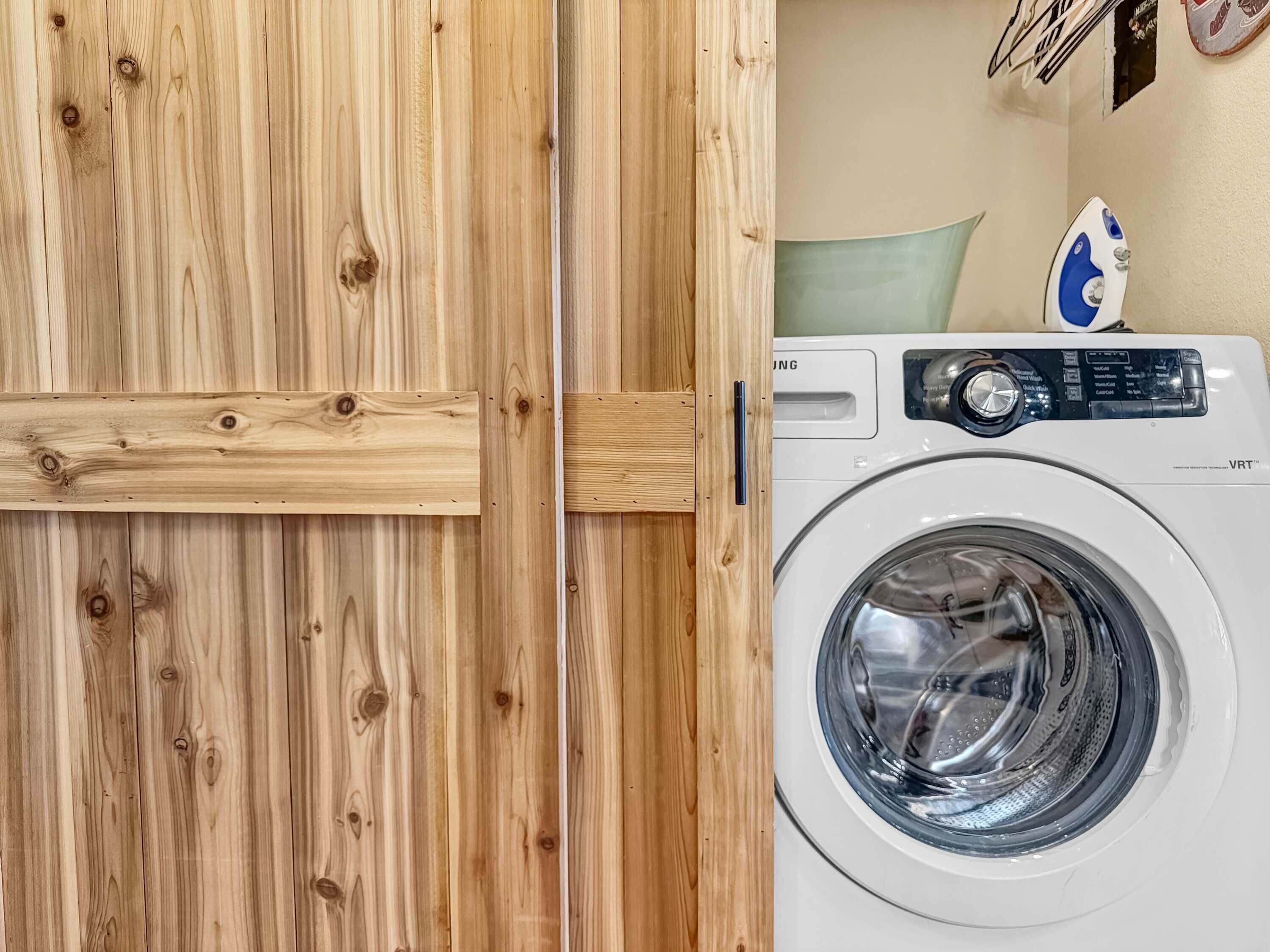 A wooden door with a handle and a white washing machine with a control panel.