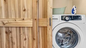 A wooden door with a handle and a white washing machine with a control panel.