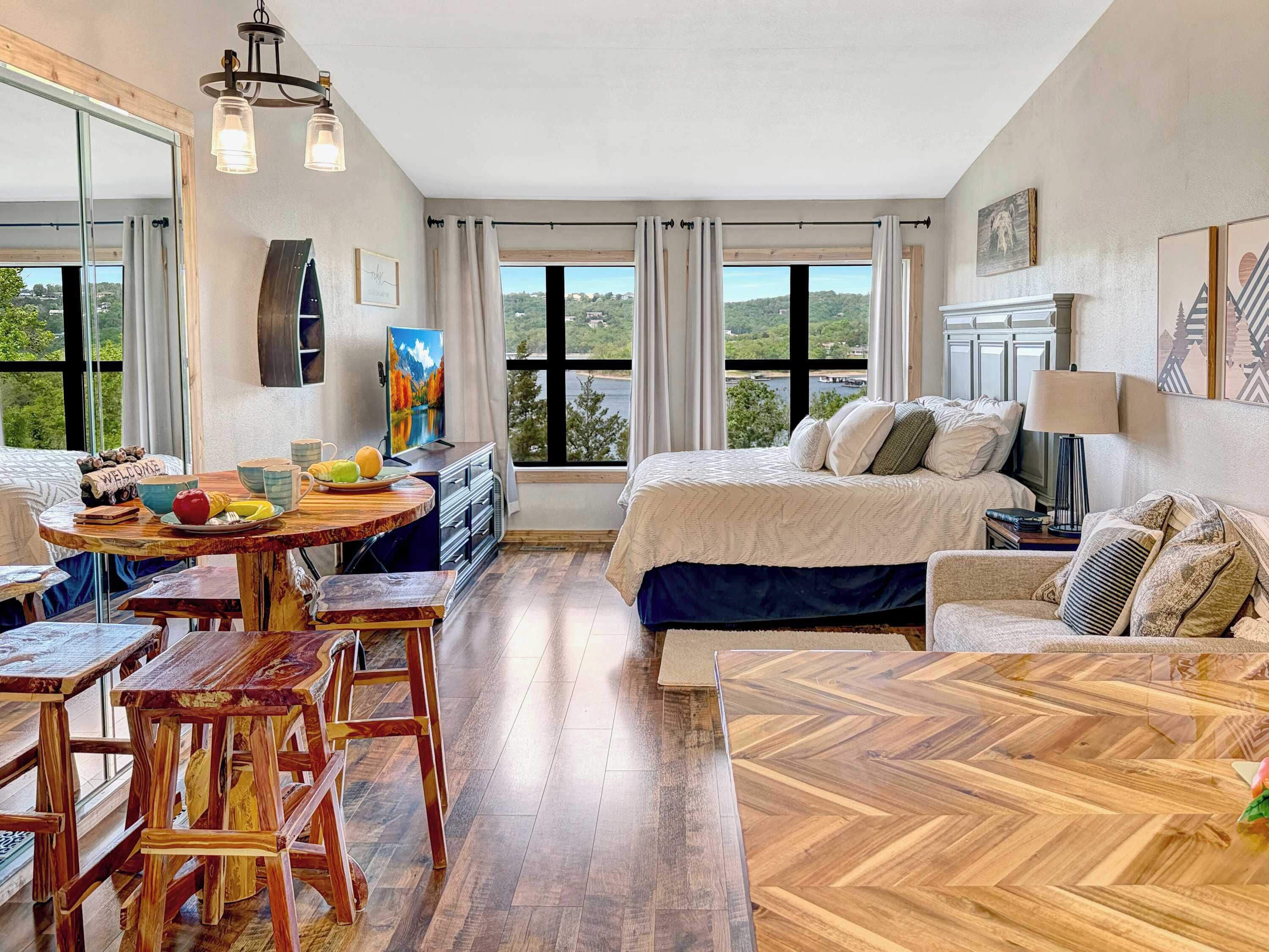 A spacious room with a bed, a dining area, and a view of the outdoors.