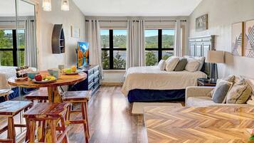 A spacious room with a bed, a dining area, and a view of the outdoors.