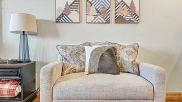 Ein gemütliches Wohnzimmer mit einer Couch, einer Lampe und drei gerahmten Kunstwerken an der Wand.