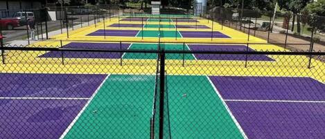 A multi-colored basketball court enclosed by a chain-link fence.