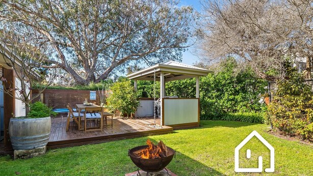 Un patio trasero con una chimenea, un porche cubierto y una terraza de madera.