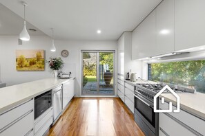 A modern kitchen with a central island, a stove, and a large window. - The Sorrento Sojourn *1 NIGHT FREE* Luxury Spa Retreat (Sorrento)