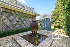 A garden with a large planter, a brick wall, and a wooden fence. - The Sorrento Sojourn *1 NIGHT FREE* Luxury Spa Retreat (Sorrento)