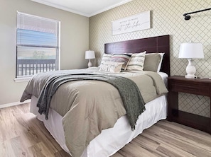A bedroom with a bed, bedside tables, a window with blinds, and a wall-mounted lamp. - Beautiful Lake View, spacious, pool, pickleball (Kimberling City)