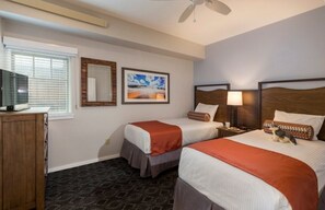 A hotel room with two beds, a TV, a ceiling fan, a window with blinds, and a framed picture on the wall. - Yellowstone | Adventure Base Retreat | Pool + Nature | 2BR (West Yellowstone)