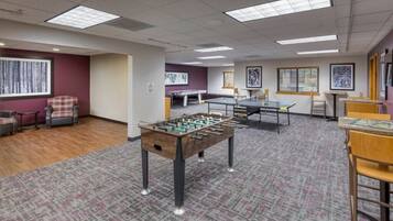 A room with a foosball table, a ping pong table, and a table tennis table.