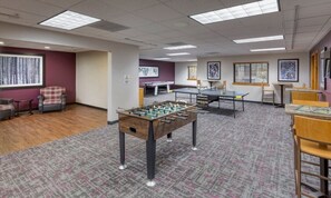 Una habitación con mesa de futbolín, mesa de ping pong y mesa de tenis de mesa.
