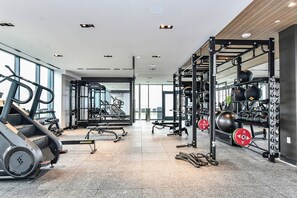 Ein modernes Fitnessstudio mit verschiedenen Trainingsgeräten, darunter Laufbänder, Kraftgeräte und Kurzhanteln.