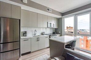 Eine moderne Küche mit Edelstahlgeräten, einer Mikrowelle und einem großen Fenster mit Blick auf die Stadt.
