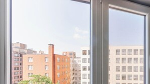 A view through a window with a cityscape in the background, featuring multi-story buildings with various architectural styles. - Blueground | Downtown, gym, nr National Mall (Washington, D.C.)