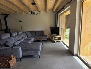 A modern living room with a sectional sofa, a small table, and a TV on a stand. - Ferienwohnung Schof by Interhome (Tschierv)