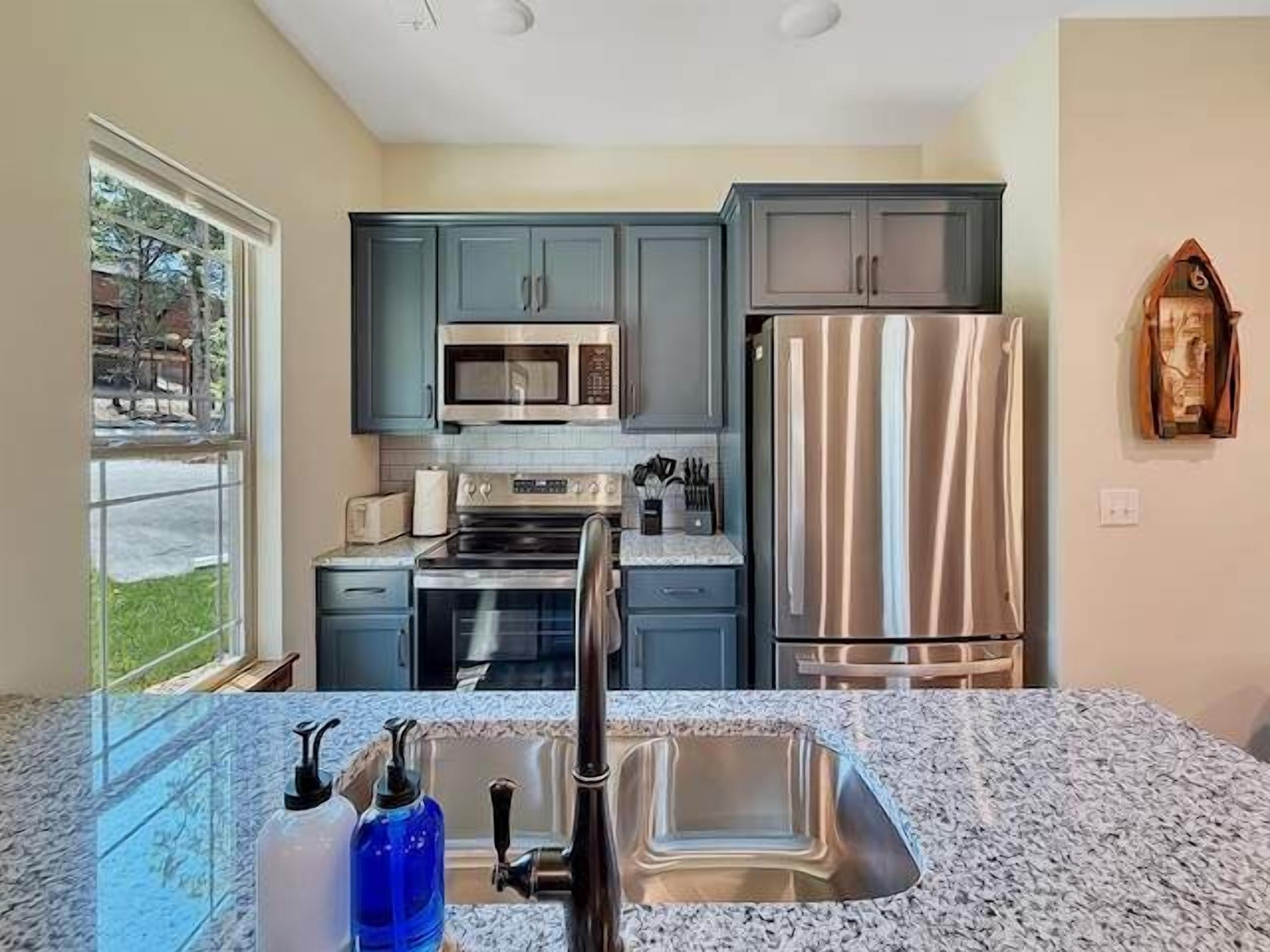 A kitchen with a stainless steel refrigerator, a microwave, and a sink with a faucet.