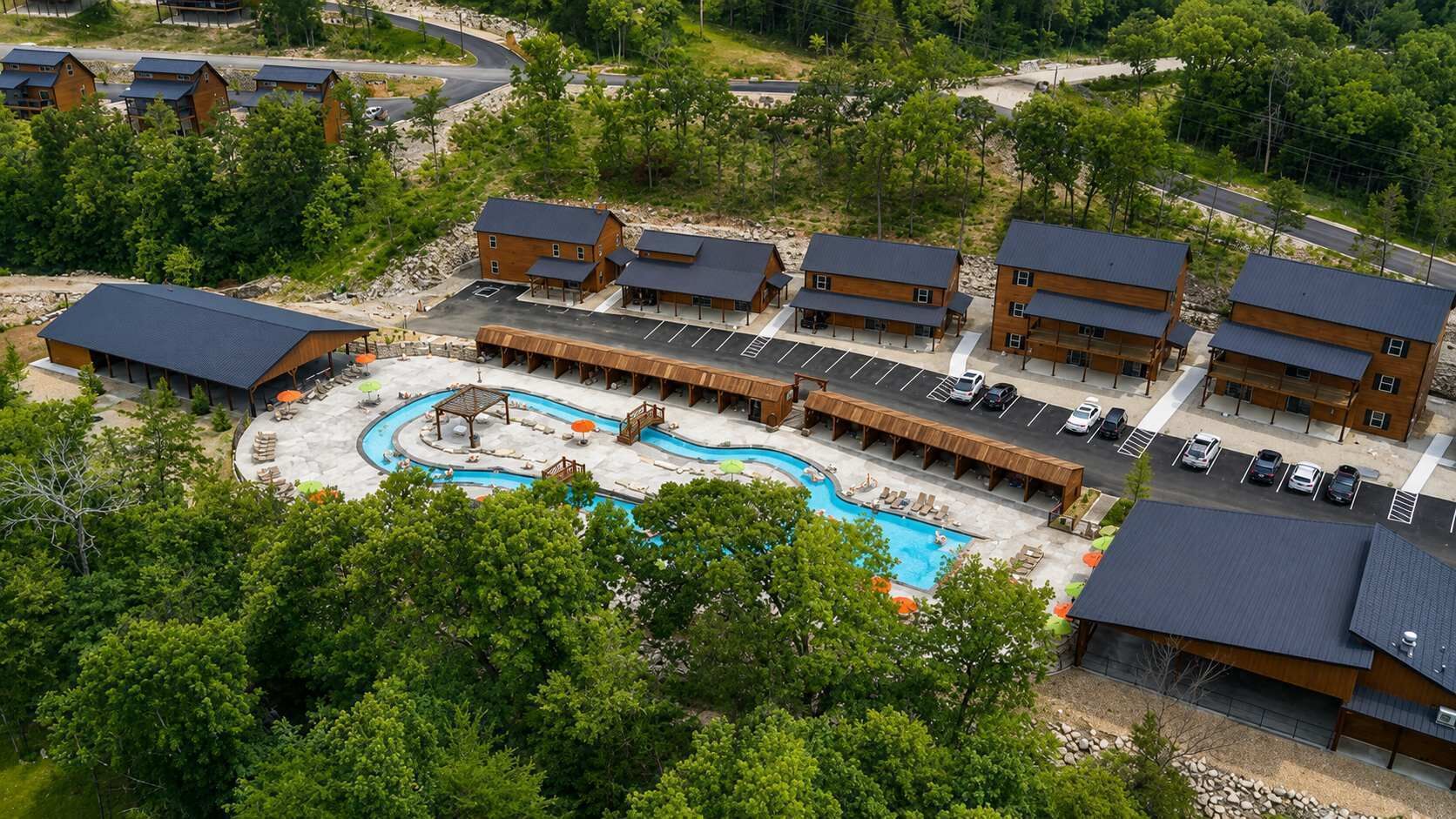 A resort with multiple wooden cabins, a central swimming pool, and a parking area.