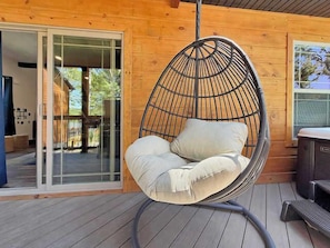 Una silla colgante con cojines sobre una terraza de madera.