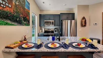 Una cocina moderna con encimeras de granito, electrodomésticos de acero inoxidable y armarios oscuros.