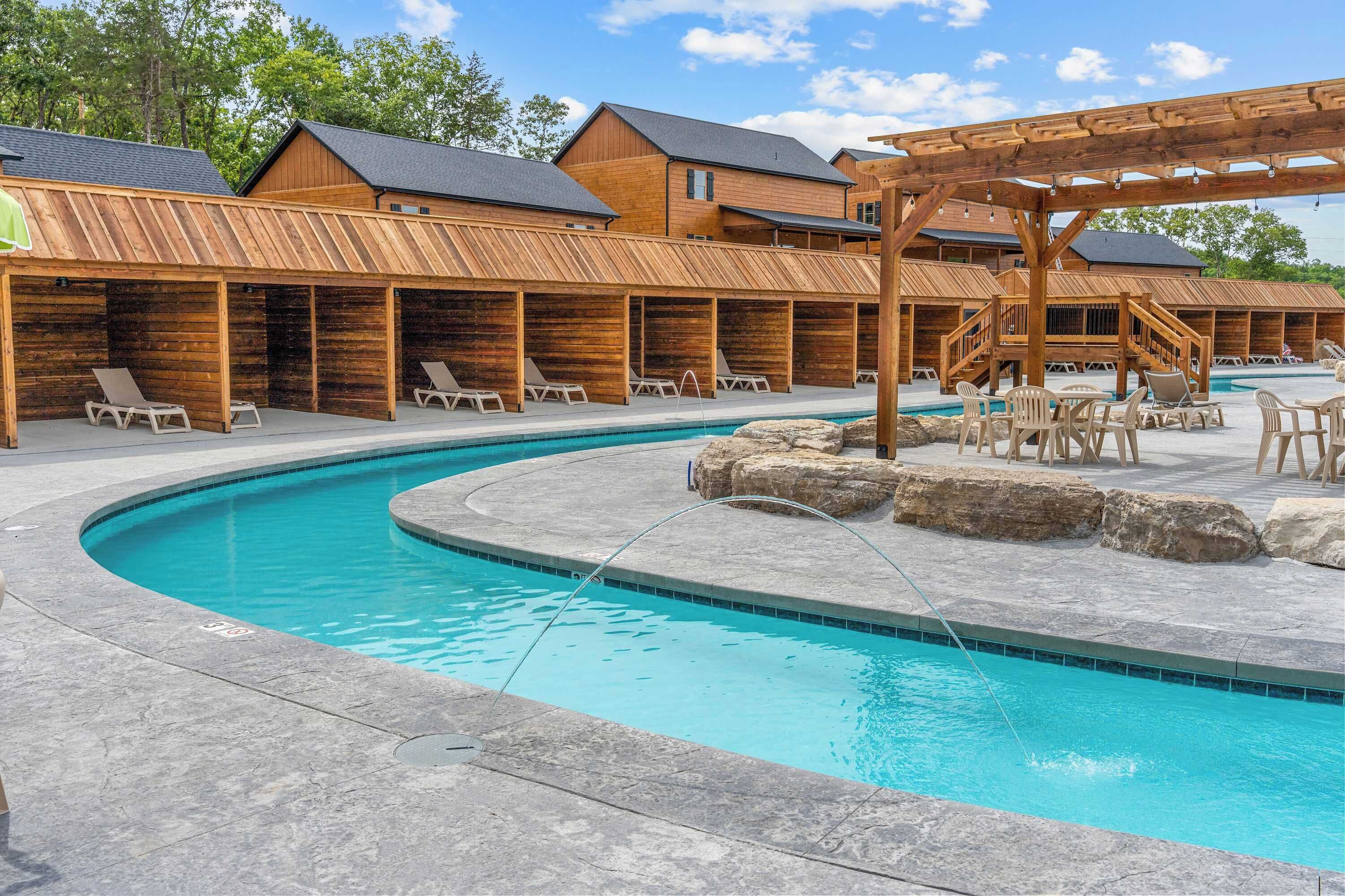 Un espace piscine comprenant des chaises longues, une terrasse en bois et une pergola en bois.