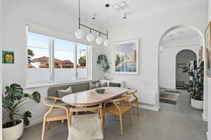 A modern dining area with a round table, wooden chairs, and a bench. - Stunning Perth Summer Home with Pool, Gardens and Outdoor Living (Mount Hawthorn)