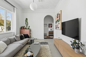 A modern living room with a sofa, a coffee table, a TV, and a bookshelf.