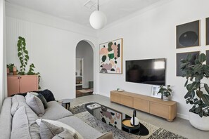 A modern living room with a sofa, a coffee table, a TV, and artwork on the wall.