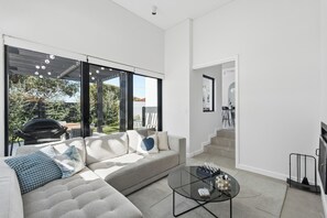 A modern living room with a sectional sofa, a glass coffee table, and a view of the outdoors.