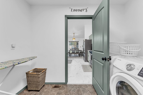 A laundry room with a washing machine, a drying rack, and a wicker basket.
