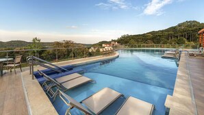 A swimming pool with lounge chairs and a view of hills.