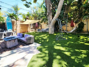 Ein Garten mit einer Hängematte, Gartenmöbeln und einem Surfbrett.