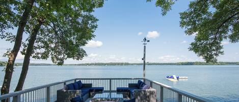 A deck with wicker furniture and a view of a lake.