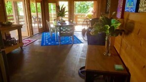 Ein Zimmer mit Holzboden, einem Esstisch mit Stühlen, einer blauen Matte und einer Topfpflanze.