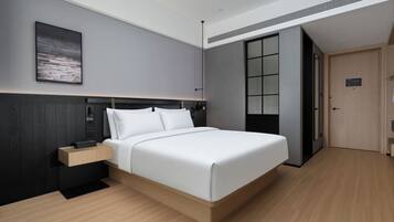 A modern bedroom with a large bed, a bedside table, a wall-mounted artwork, and a door leading to another room.