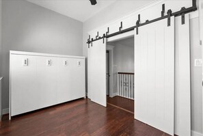 Un couloir avec une armoire blanche, une porte coulissante et un escalier.