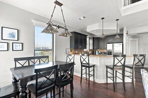 A modern kitchen with dark cabinetry, a central island, and pendant lighting.