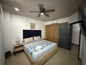 A bedroom with a bed, a nightstand, a ceiling fan, a wardrobe, and a door. - Marina Suites | Vive la Marina de Mazatlán by GPS (Mazatlán)
