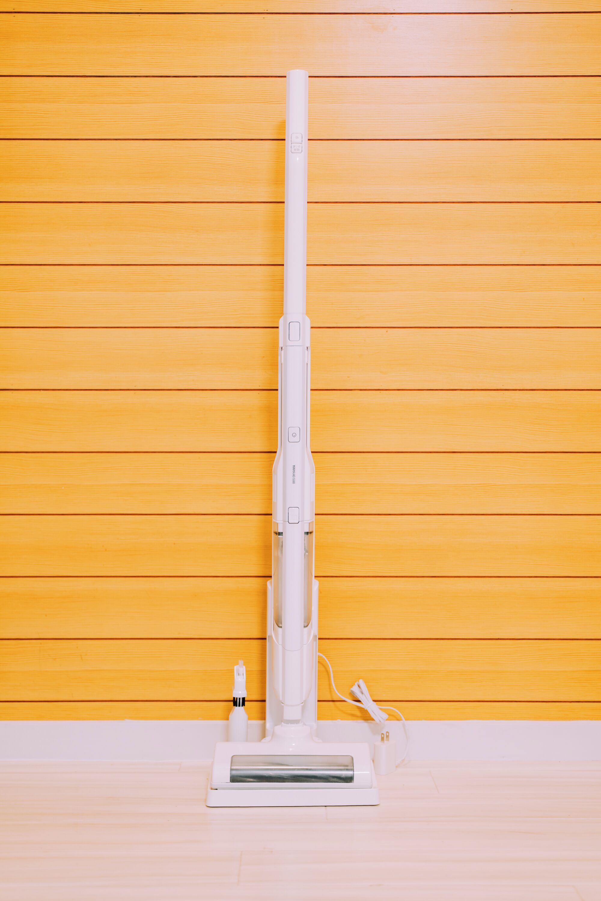 Una aspiradora blanca sobre un fondo de pared de madera.