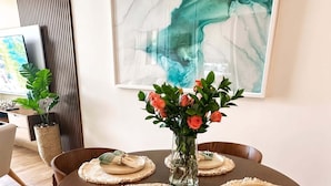 Une table de salle à manger ronde, avec des sets de table, un vase de fleurs et des chaises.