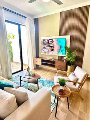 A modern living room with a flat-screen TV, a sofa, a coffee table, and a chair. - 2-bedroom apartment in lovely Punta Cana with AC and gym access (Punta Cana)