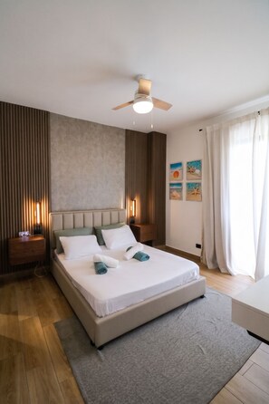 A modern bedroom with a bed, bedside tables, a ceiling fan, and artwork on the wall. - 2-bedroom apartment in lovely Punta Cana with AC and gym access (Punta Cana)