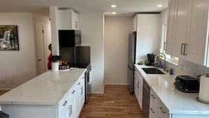 A modern kitchen with white cabinetry, a central island, and a stainless steel range hood. - Awesome Little House ! (Mountlake Terrace)